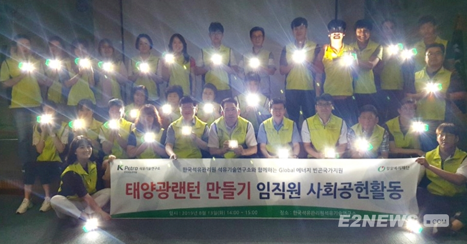 ▲오창 한국석유관리원 석유기술연구소 임직원들이 태양광랜턴 만들기 봉사활동을 펼치고 기념사진을 찍고 있다.