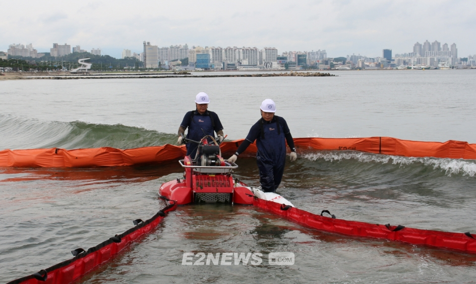 ▲해양환경공단 직원들이 오일스키머를 투입해 해안으로 밀려온 기름을 수거하고 있다.