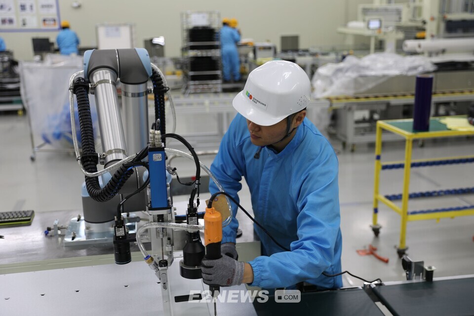 협동로봇과 함께 직원이 작업을 하고 있다.