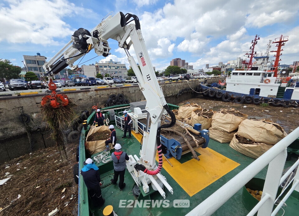 해양환경공단 관계자가 청항선 등 장비를 이용, 항구에 부유하는 쓰레기를 수거하는 있다.